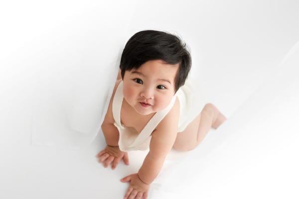 Baby crawling on a white blanket, photographed from above