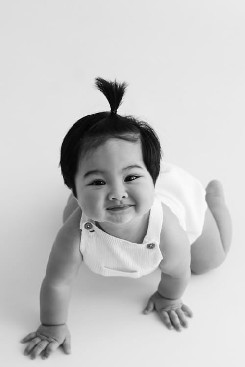 Baby crawling towards the camera on a white floor, smiling