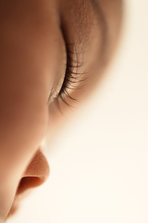 Macro detail of a newborn's eyelashes and ear