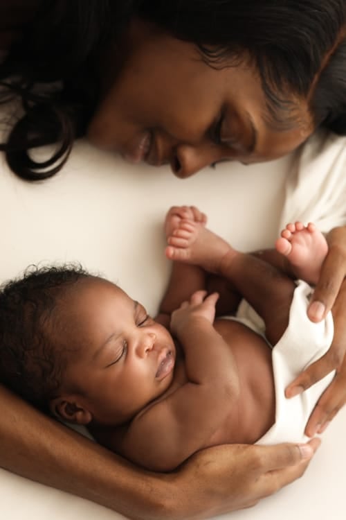 Mother lying cheek to cheek with her newborn, both with dark hair