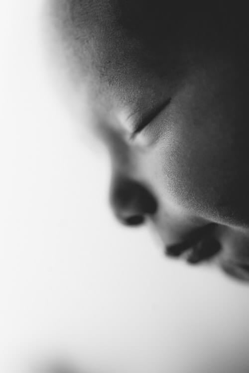 Profile of a sleeping newborn against a bright white background