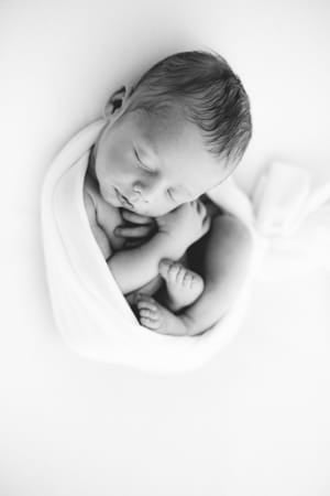 Newborn wrapped in white, photographed from directly above