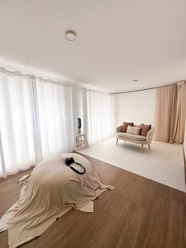 The shooting room: a beanbag dressed in cream fabric, voile curtains along the whole window wall and a small sofa at the far end