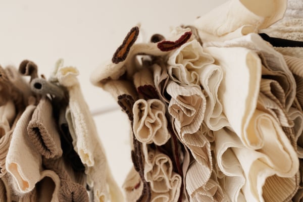 Close view of knitted wraps and bonnets hanging together, the textures side by side