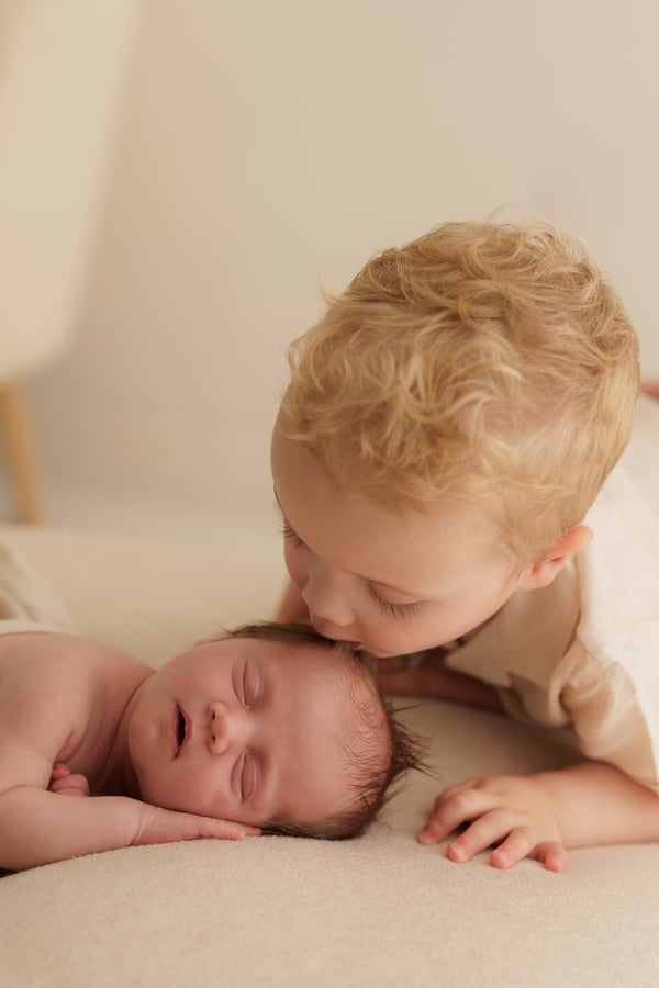 A big brother kissing his newborn sister's head, close in