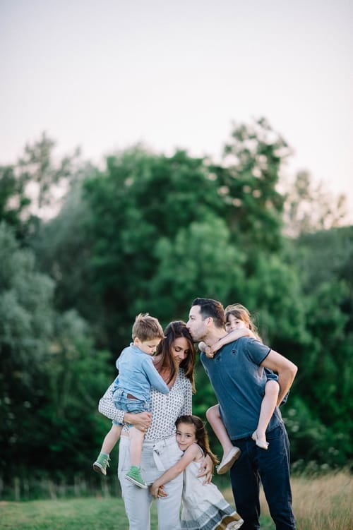 Francesca's family standing together at dusk, the children carried and held