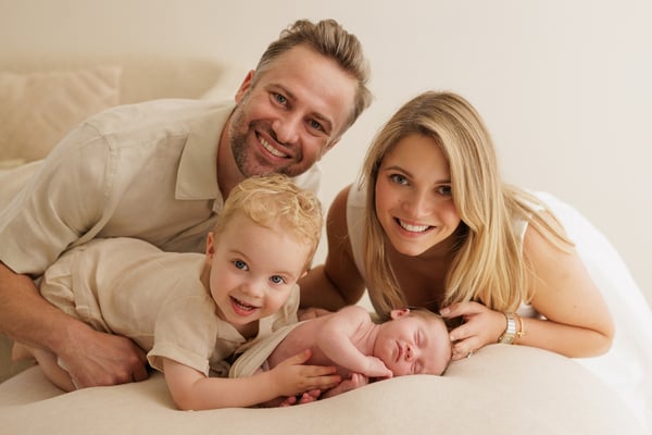 Both parents and the big brother lying around the sleeping newborn