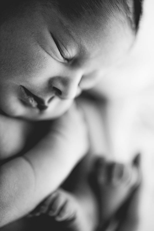 Close-up of a sleeping newborn's face against a white blanket