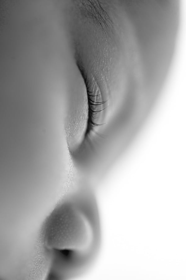 Extreme close-up of a newborn's closed eye and lashes, in black and white
