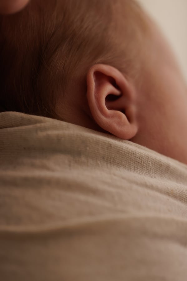 Close view of a newborn's ear and the fold of the wrap around them