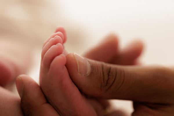 A newborn's foot resting in a parent's open hand