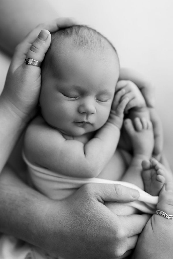 Neonato addormentato raccolto fra due mani
