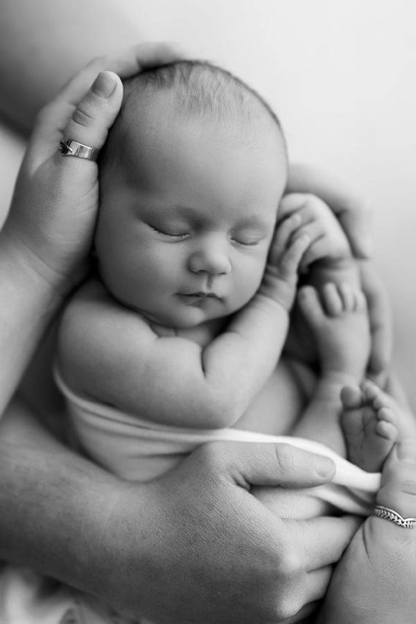 Neonato addormentato raccolto fra due mani