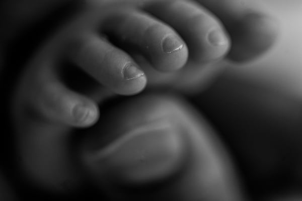 Extreme close-up of a newborn's toes in low light, in black and white
