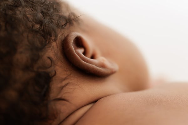 Close-up of a sleeping newborn's ear and dark curls