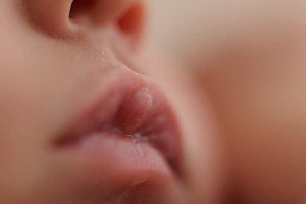 Macro of a sleeping newborn's lips and chin, with the ear behind