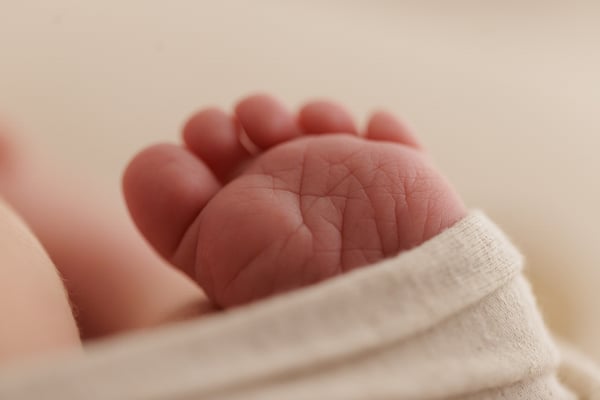 Macro of the sole of a newborn's foot and the toes, just above a cream wrap