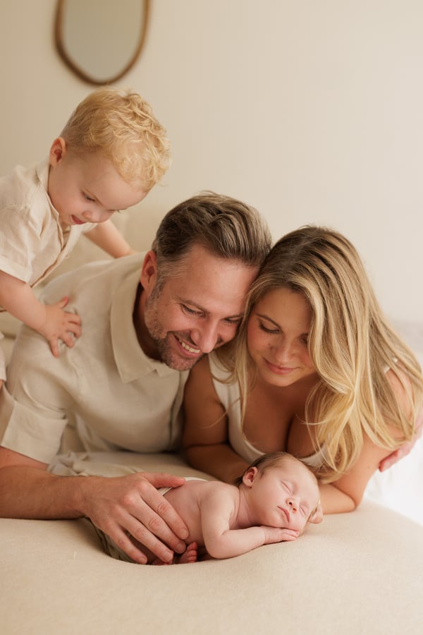 Both parents and the big brother gathered behind the sleeping newborn