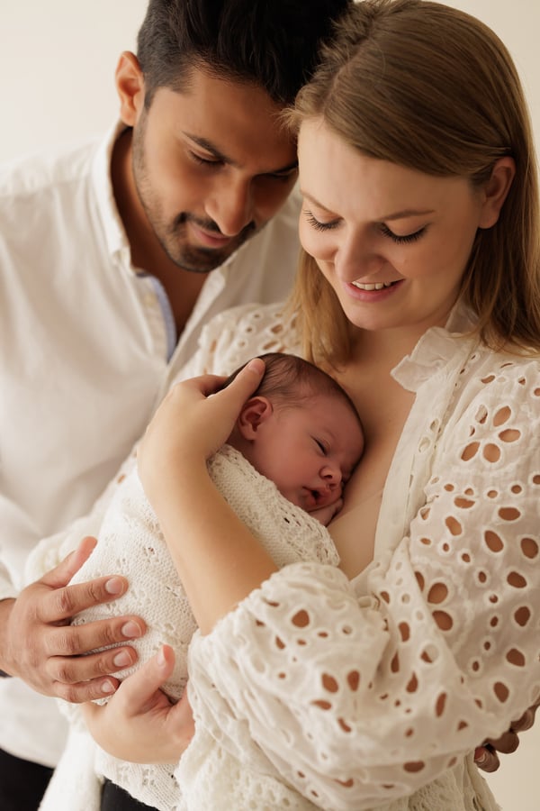 Both parents looking down at their newborn held in the mother's arms