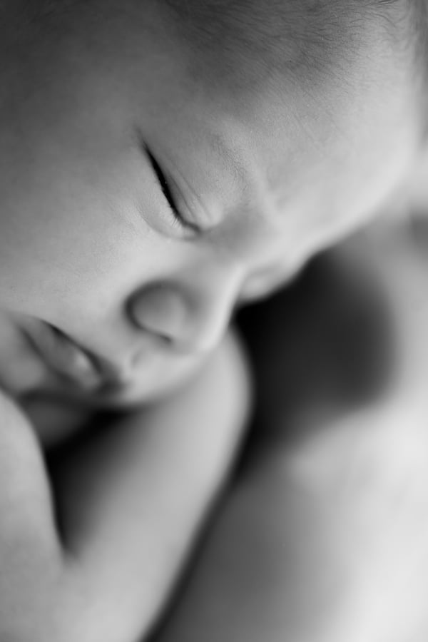 Close view of a sleeping newborn's closed eye and nose, in black and white