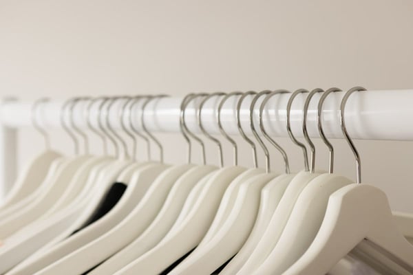 A close row of pale wooden hangers on a white rail