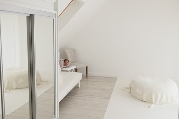 The shooting room seen past the mirrored wardrobe, with a sofa and an armchair for parents