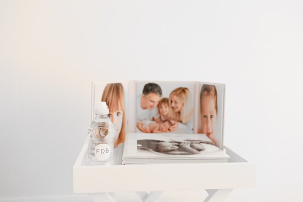 A bottle of water and an open fine art album on a white side table
